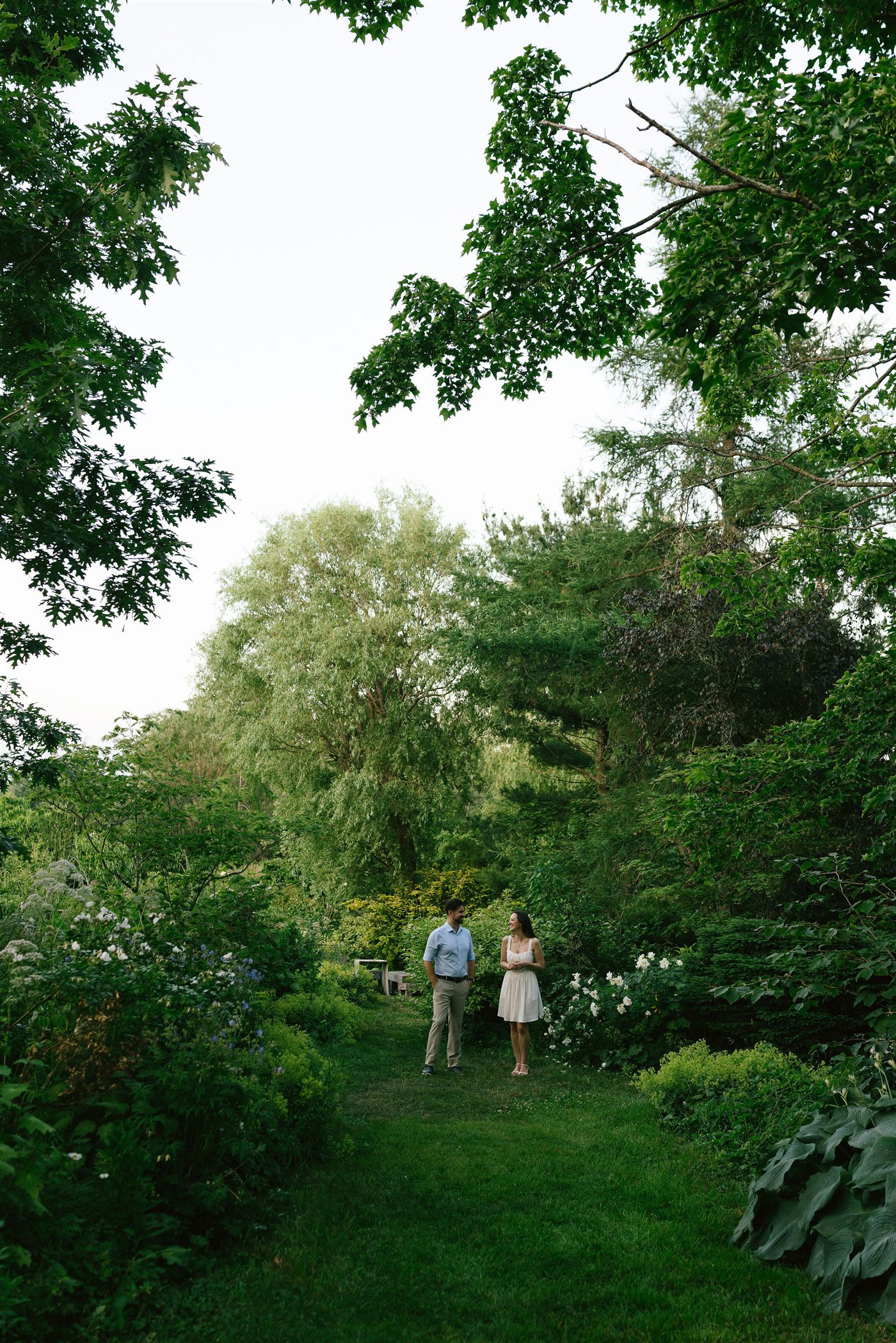 Danielle and Brenden walking together through a lush garden