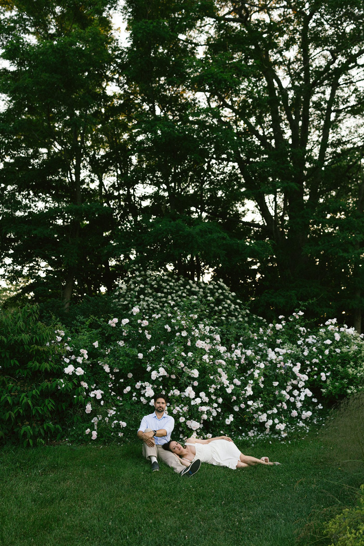 Danielle reclining beside Brenden in front of garden roses